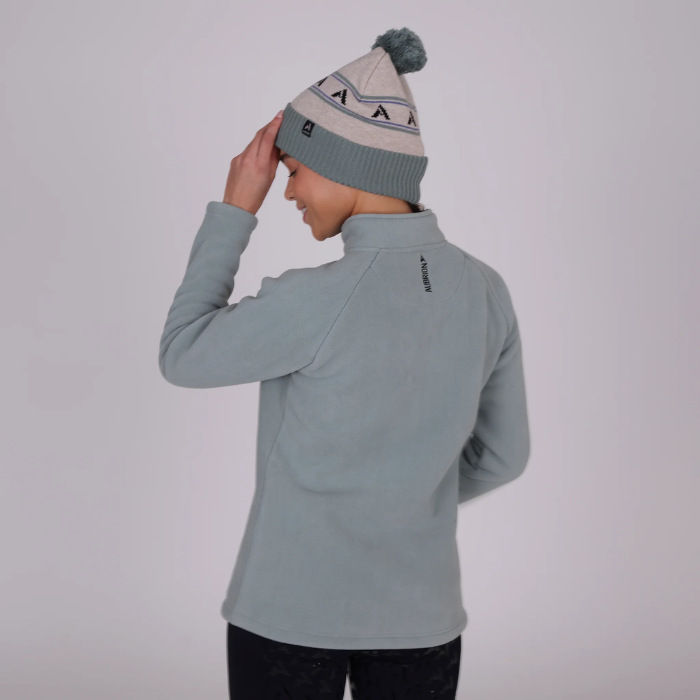 Person wearing a light blue fleece jacket and matching beanie on a plain background