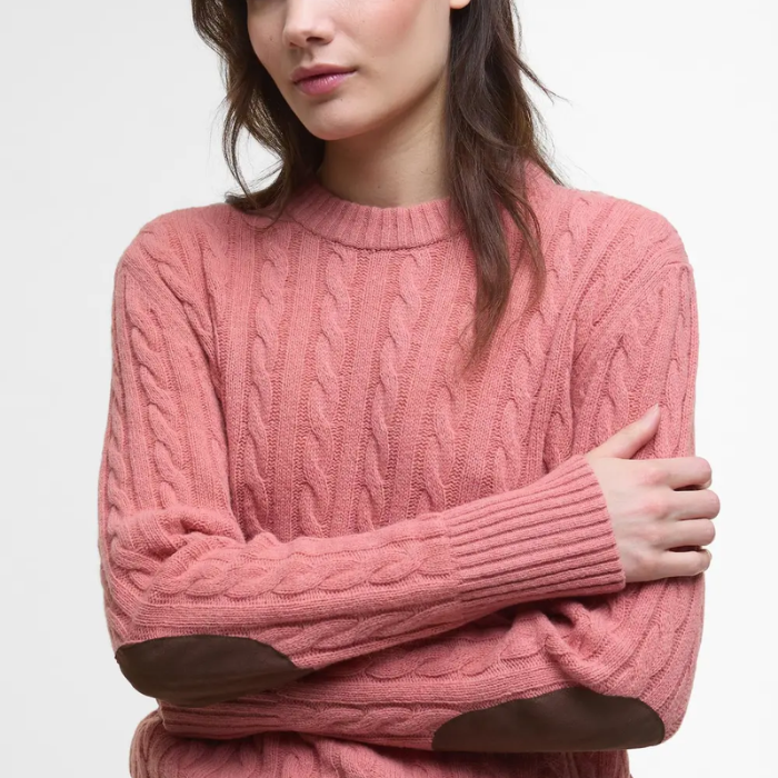 woman wears pink cable knit jumper with elbow patches