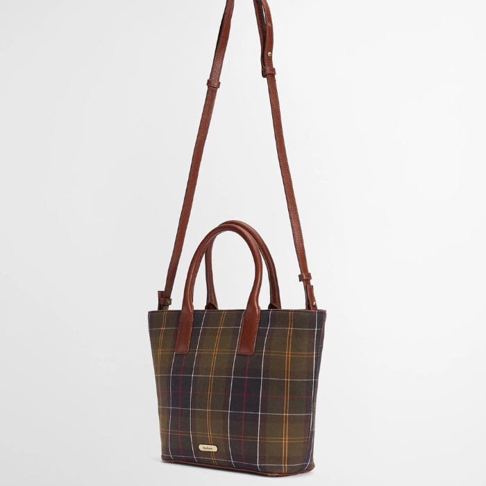 Tartan handbag with brown leather straps on a light grey background
