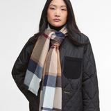 Woman wearing a tartan scarf and black quilted jacket on a white background