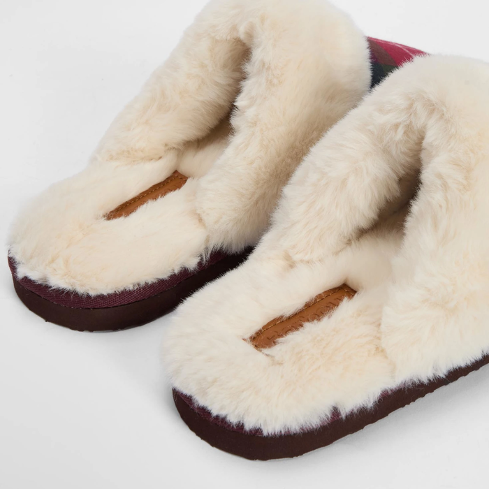 Pair of slippers with white fur lining and brown soles on a light grey background