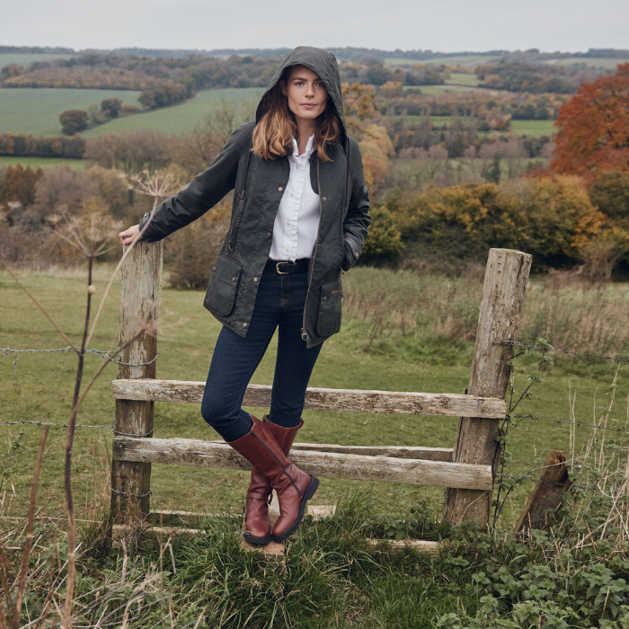 Woman standing on a wooden stile in a countryside setting