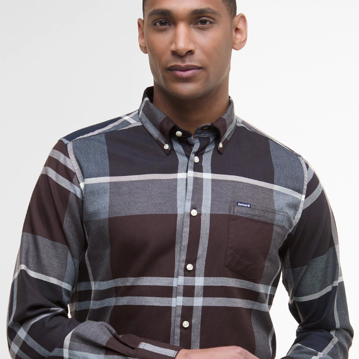 Man wearing a tartan shirt with a visible brand logo on a plain background