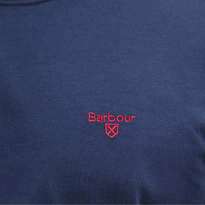 Close-up of a navy blue shirt with a red Barbour shield logo on a matching background