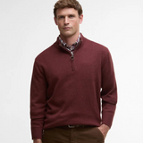 Man wearing a red Barbour sweater with a plaid shirt underneath on a white background