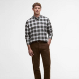 Man wearing a plaid Barbour shirt and brown trousers on a white background