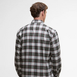 Person wearing a plaid Barbour shirt on a plain background