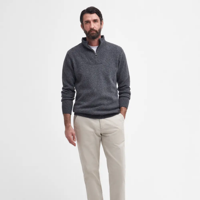 Man wearing a grey knitted jumper and beige chinos on a white background