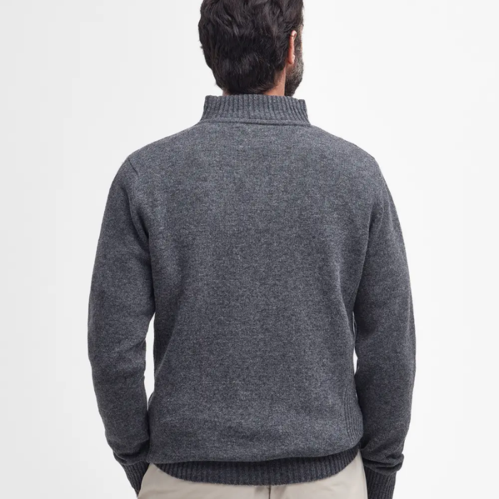 Person wearing a grey knitted jumper on a plain background