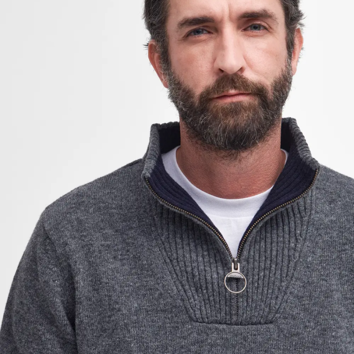 Man wearing a gray knitted jumper with a white background