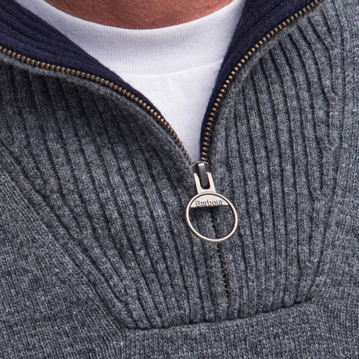 Close-up of a grey knitted jumper with a zipper and 'Barbour' brand tag.