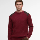 Man wearing a red Barbour jumper with dark shoulder panels on a light gray background