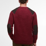 Red Barbour jumper with dark elbow patches worn by a person on a white background