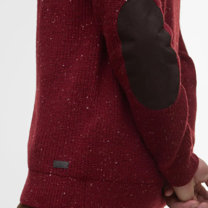 Close-up of a red textured jumper with a brown elbow patch on a light gray background