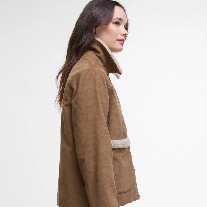 Woman wearing a beige Barbour coat with white lining on a light gray background