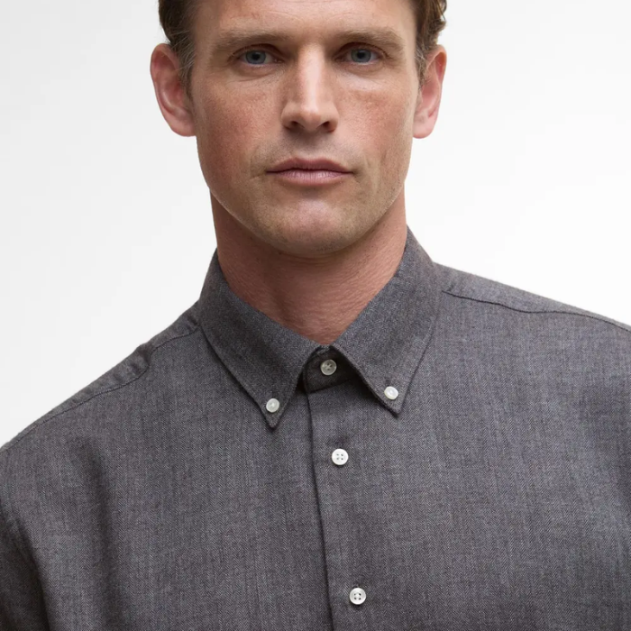 Man wearing a grey button-up shirt against a plain background