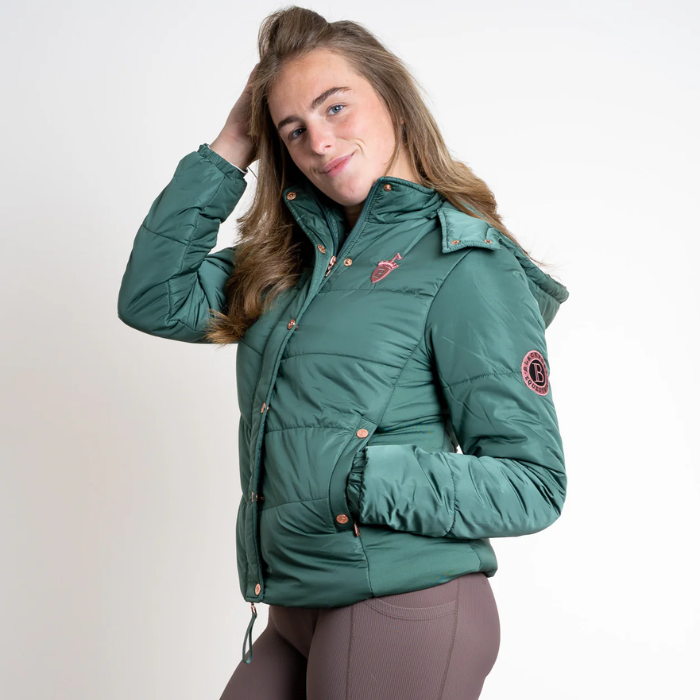 Woman wearing a green puffer jacket on a plain background