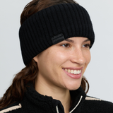 LeMieux AW26 Clara Rib Headband Variant Colouir Black.
A smiling woman wearing a black ribbed knit headband with a small black brand tab that reads 'LeMieux'.