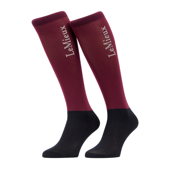 LeMieux AW26 Competition Socks 2 pack Variant Colour Blackberry.
A pair of knee-high socks in blackberry and black, featuring the brand name 'LeMieux' printed in white script on the upper leg, set against a plain light gray background.
