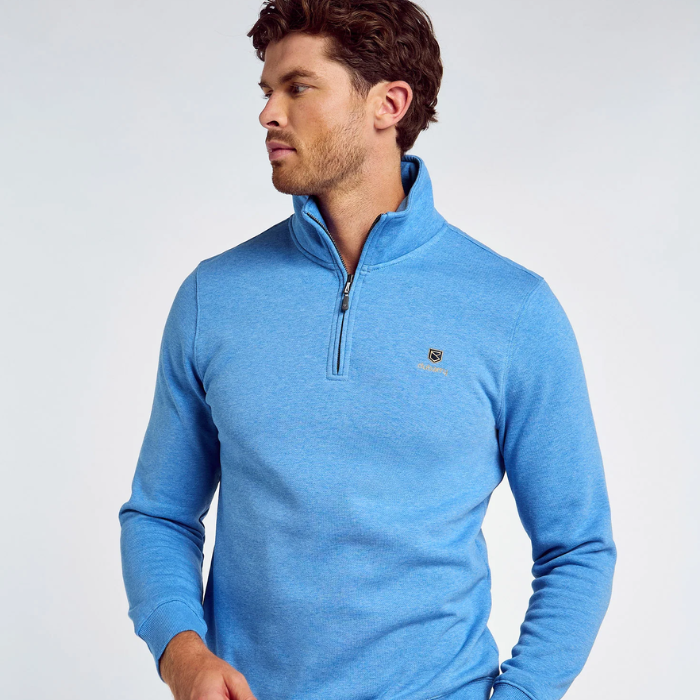 Man wearing a blue sweater with a small logo on a light grey background