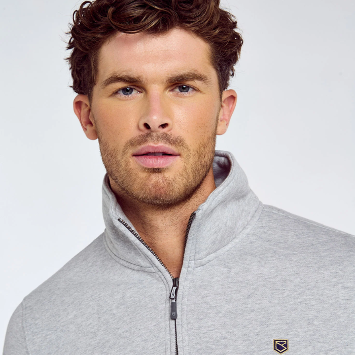 Close up of a man wearing a zipped grey sweatshirt on a light grey background