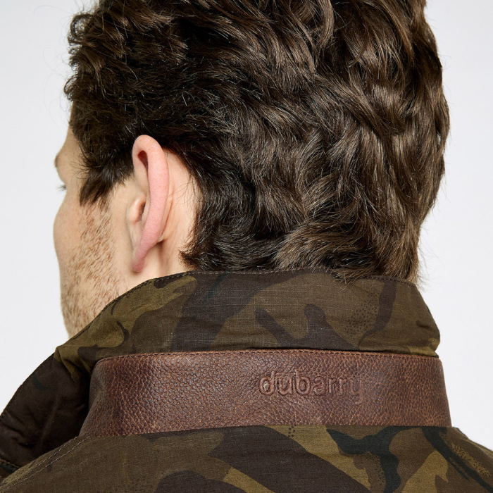 Person wearing a camouflage jacket with a brown leather collar, featuring the Dubarry brand logo.