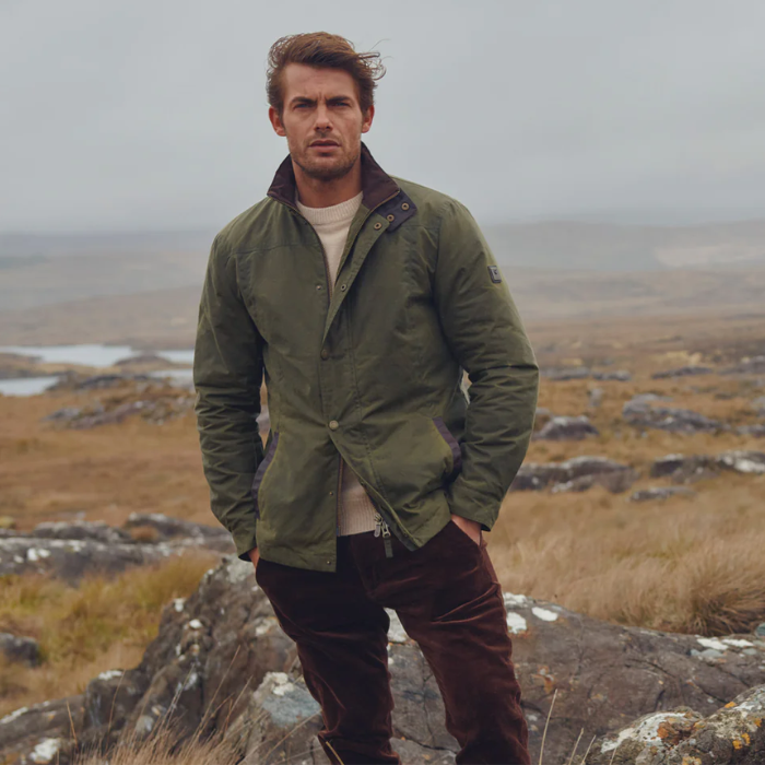 Man wearing a green jacket standing on a rocky landscape