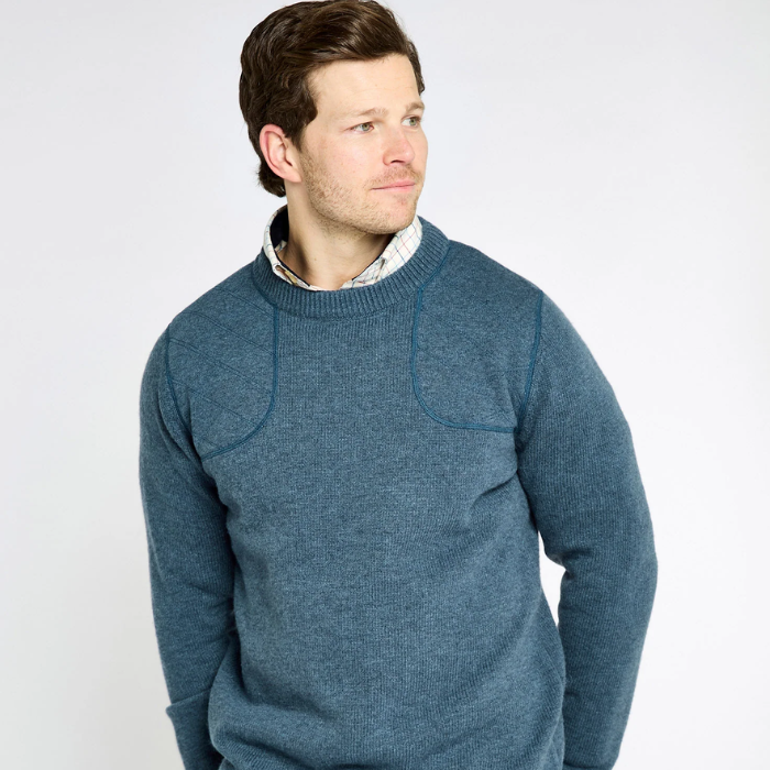 Man wearing a blue knitted jumper on a light background