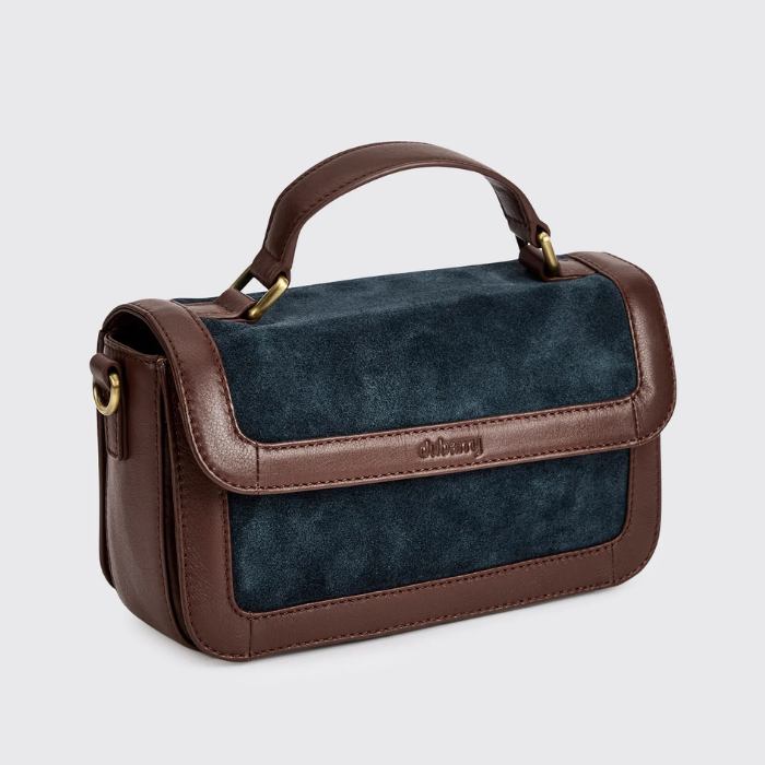 brown leather and navy suede boxy handbag against a grey background