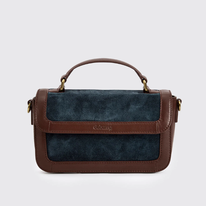 brown leather and navy suede boxy handbag against a grey background