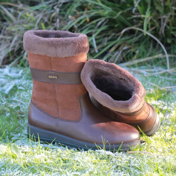 Pair of brown winter boots with fur lining on a frosty grass background
