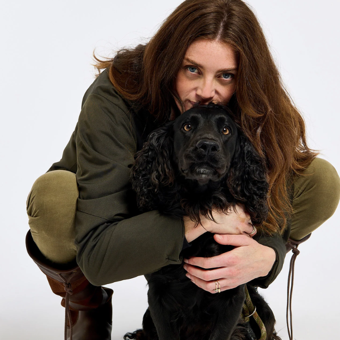 lady wearing a green coat with a black dog and a white background