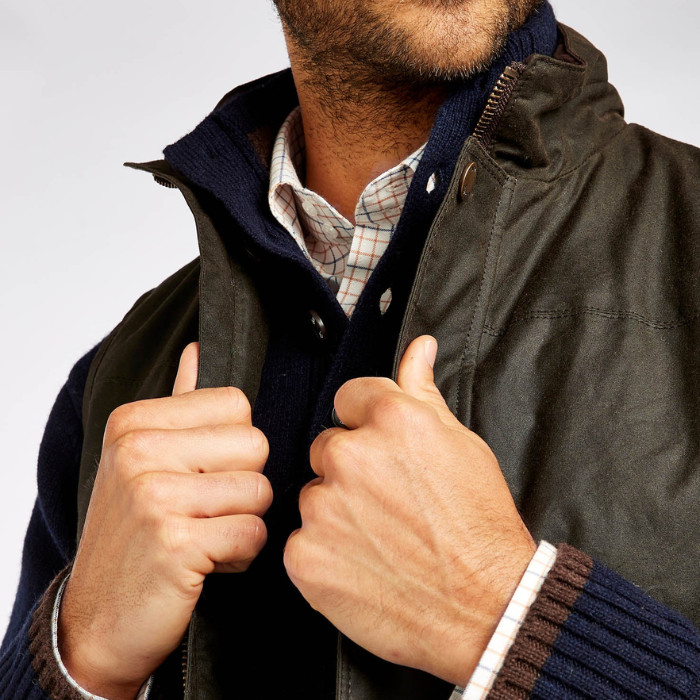 Person wearing a dark jacket with a plaid shirt underneath, giving a thumbs-up gesture.