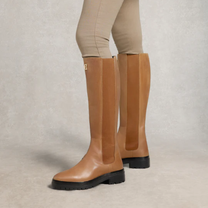 Tan knee-high boots with a brand logo on a neutral background