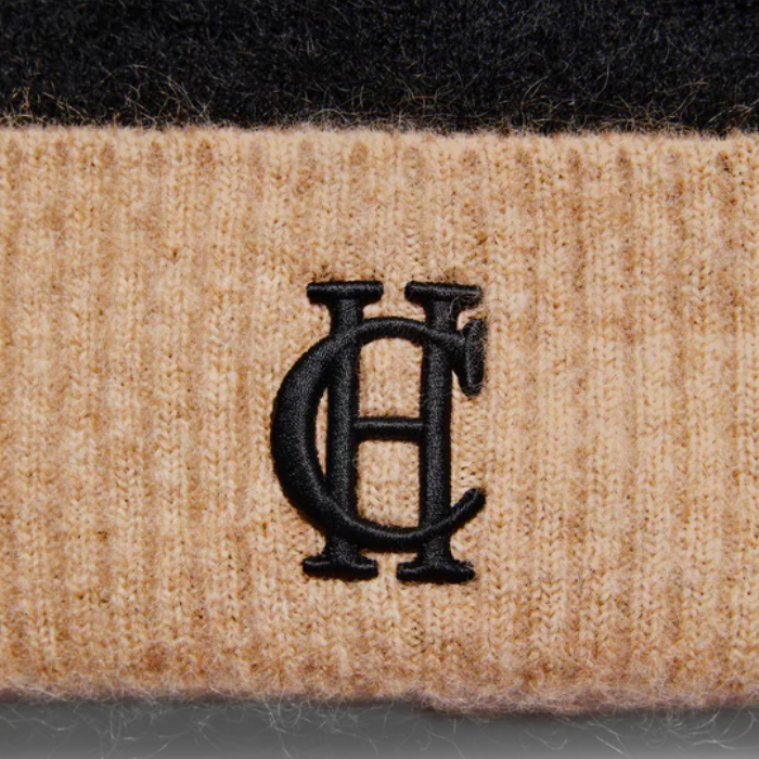 Close-up of a textured fabric with a black embroidered logo on a dark background