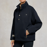 Person wearing a navy blue jacket with their hand in the pocket on a grey background