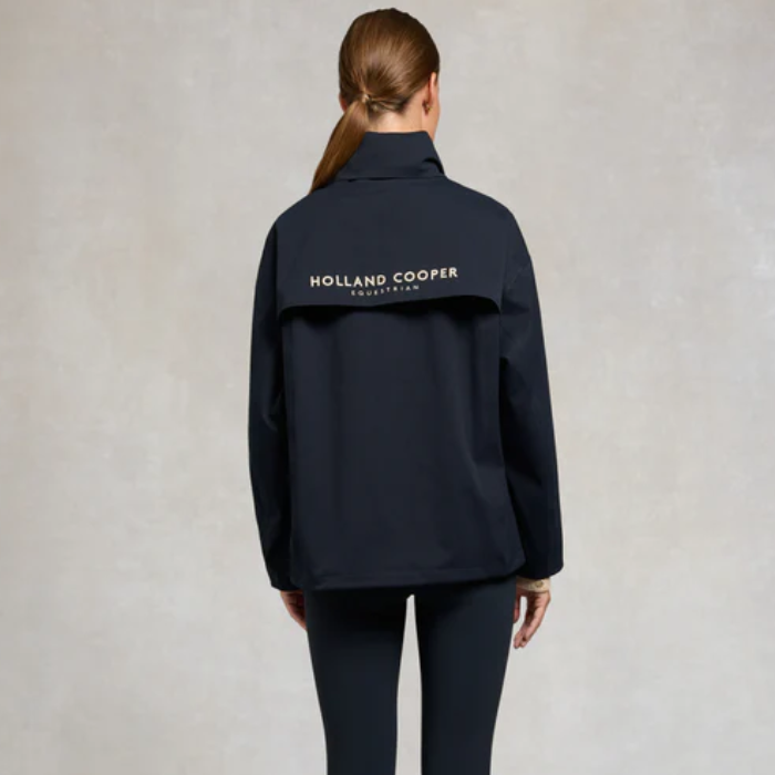 Person wearing a navy jacket with 'Holland Cooper' branding on the back against a neutral background