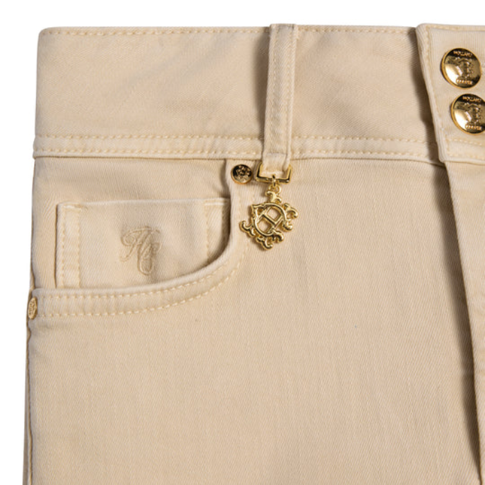 Close-up of beige jeans with a brand logo on the pocket and gold buttons.