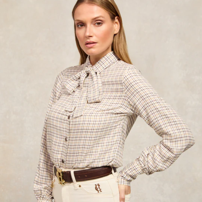 Woman wearing a checkered shirt with a bow tie against a plain background
