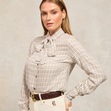 Woman wearing a checkered shirt with a bow tie against a plain background