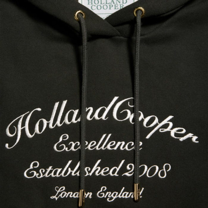 Dark green hoodie with 'Holland Cooper' branding and text on a blurred background