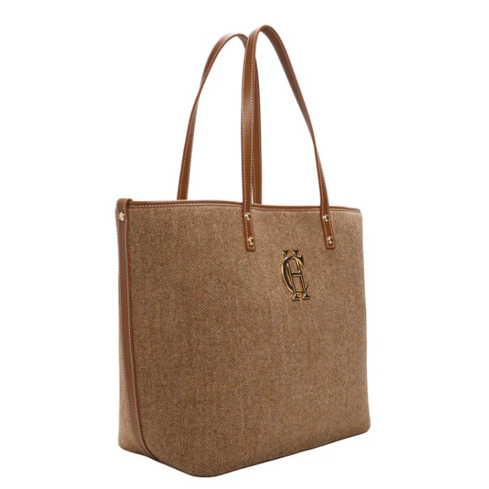 light brown herringbone tote bag with HC gold harware logo on white background