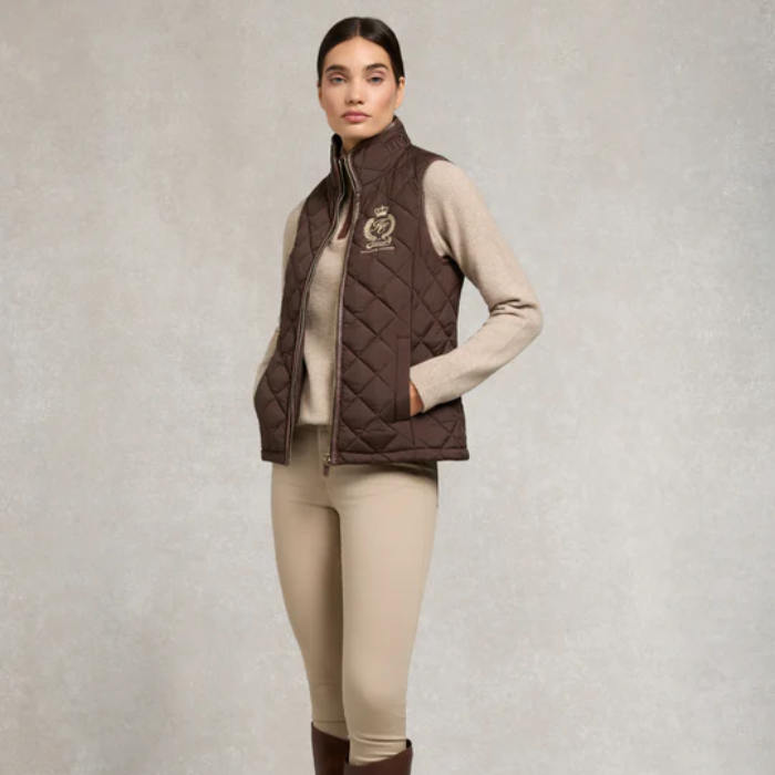 Woman wearing a brown quilted gilet with a logo on a light grey background