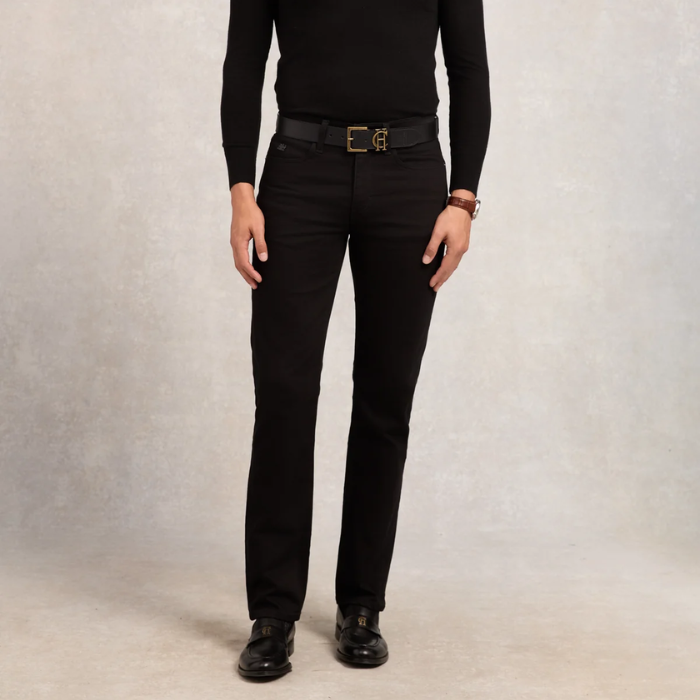 Person wearing black jeans with a belt on a neutral background