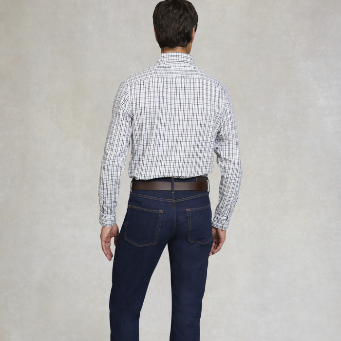 Man wearing a checkered shirt and dark jeans against a plain background