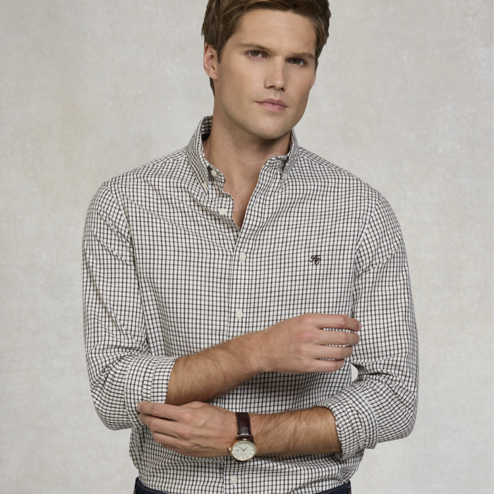 Man wearing a checkered shirt with a subtle brand logo on a plain background