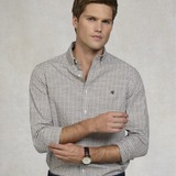 Man wearing a checkered shirt with a subtle brand logo on a plain background