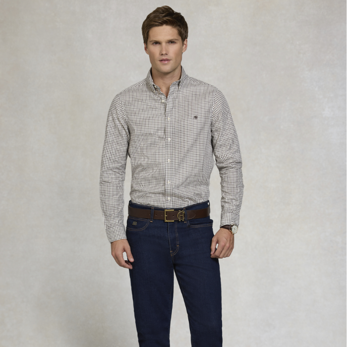 Man wearing a checkered shirt and dark jeans against a plain background