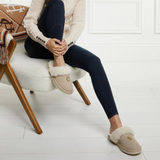 Person wearing beige slippers with a fluffy interior, sitting on a chair.