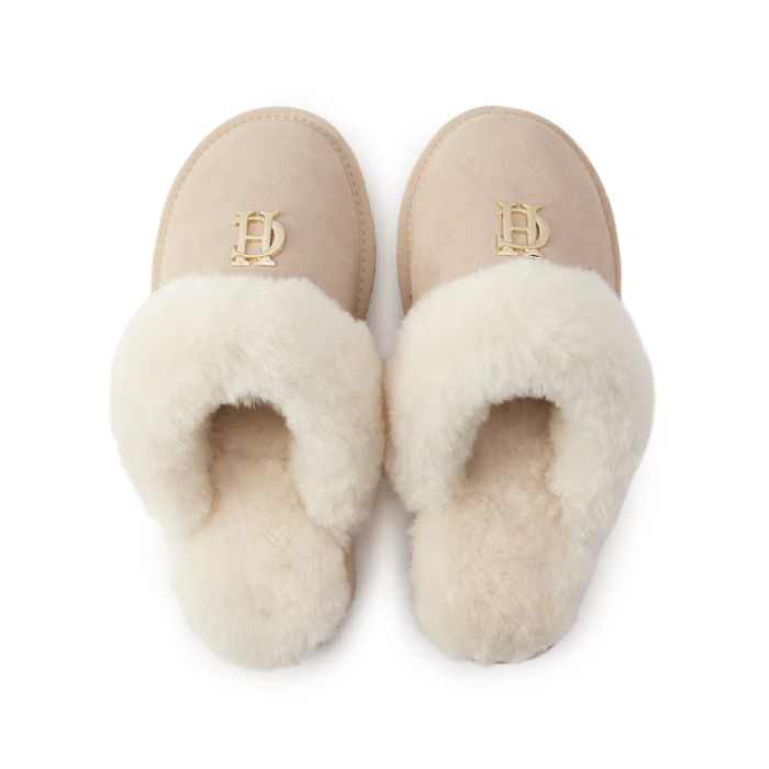 Pair of beige slippers with white fur lining on a white background